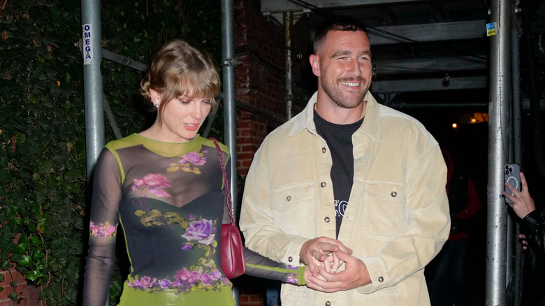 Travis Kelce and Taylor Swift walking together, holding hands