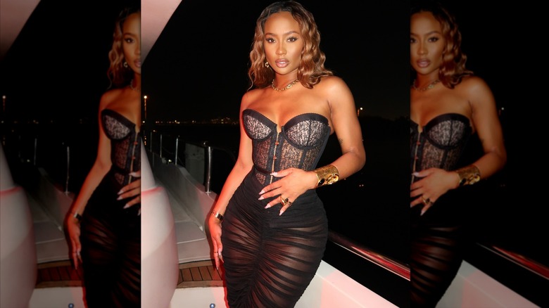 Kayla Nicole in a corset and sheer black skirt, at night, on a boat.