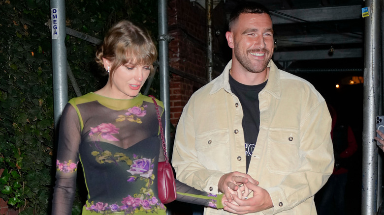 Travis Kelce and Taylor Swift walking out of a restaurant