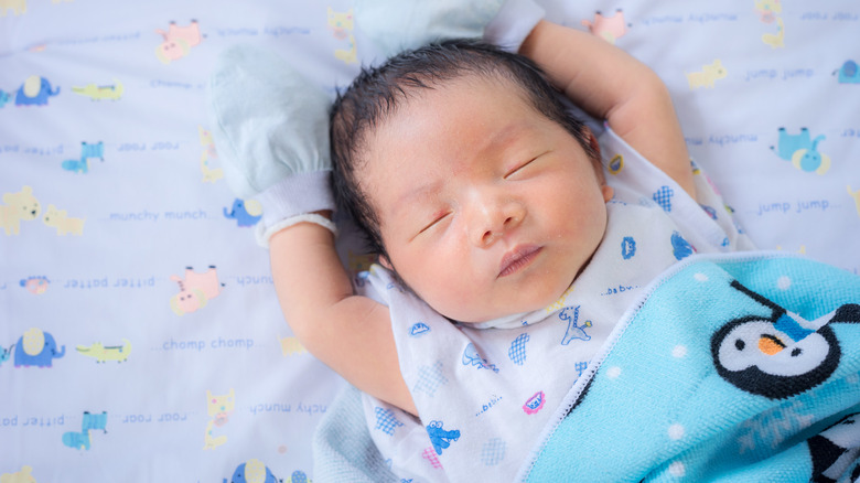 Newborn baby boy with penguin blanket sleeping