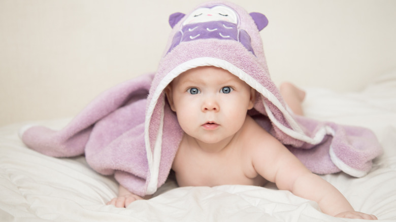 Serious baby girl in a hooded towel