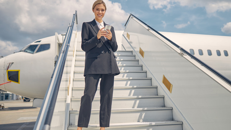 Woman on airplane stairs wearing a pantsuit