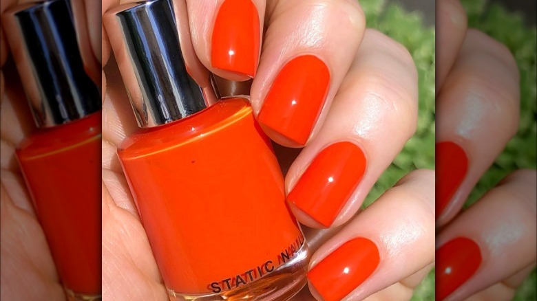 hand with orange nails holding polish