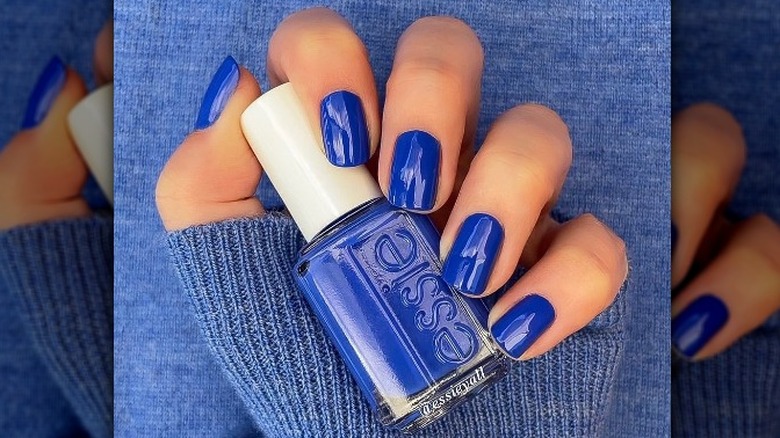 hand with royal blue nails holding polish 