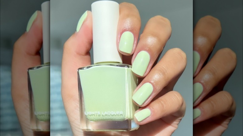 hand with green pastel nails holding polish