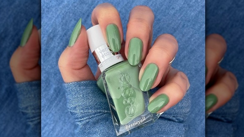 hand with green nails holding polish