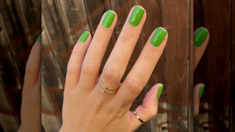 hand with green nails against wood