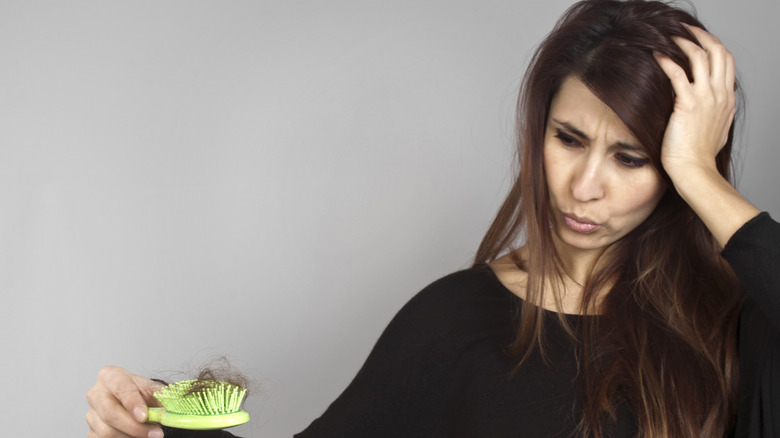 Woman with hair on brush looks concerned