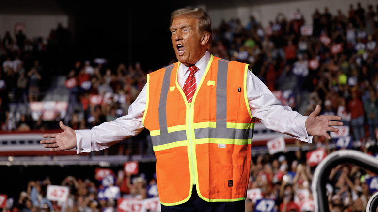 Donald Trump shouting on rally stage in reflective orange vest