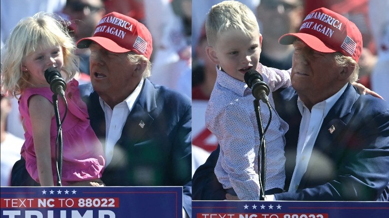 Donald Trump holding his grandchildren behind a podium