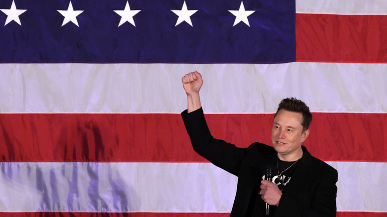 Elon Musk with fist in the air in front of an American flag