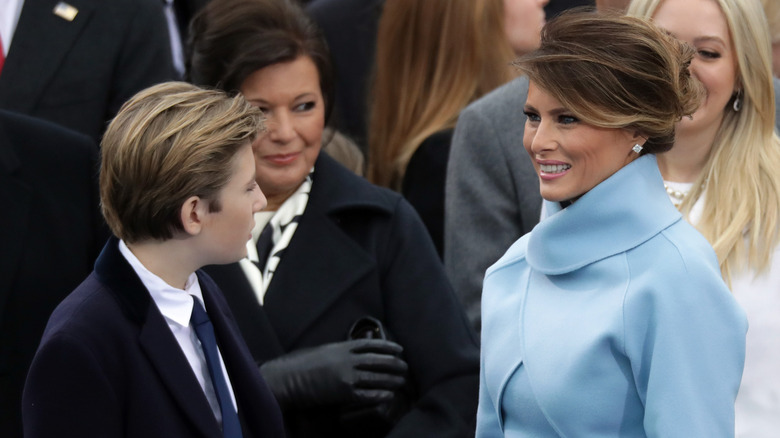 Barron Trump talking to Melania Trump as she smiles at him