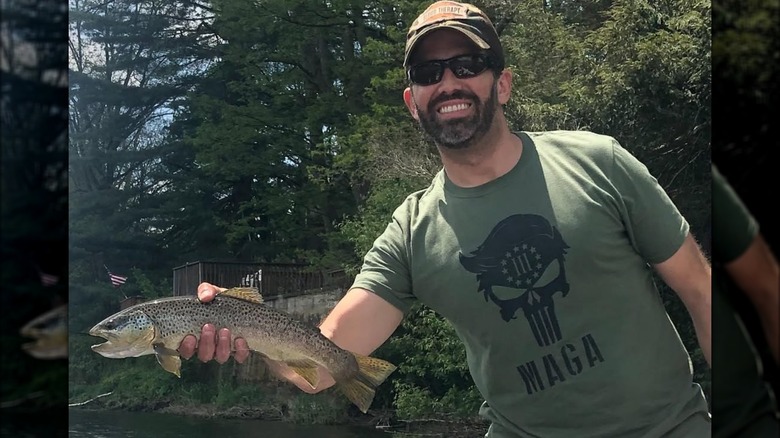 Donald Trump Jr. wearing a green MAGA shirt and holding a fish