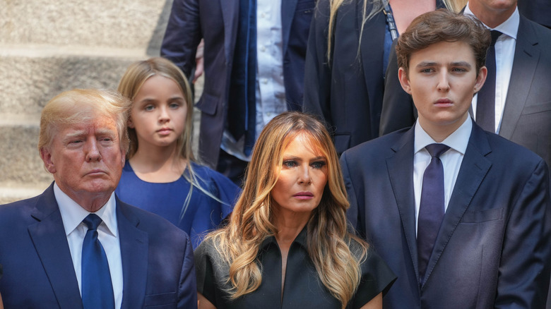 Donald, Melania, and Barron Trump looking somber