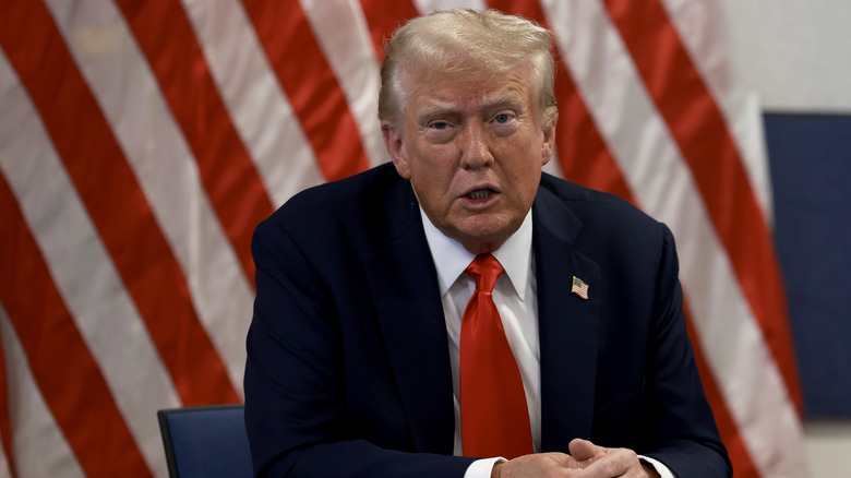 Donald Trump speaking in front of an American flag