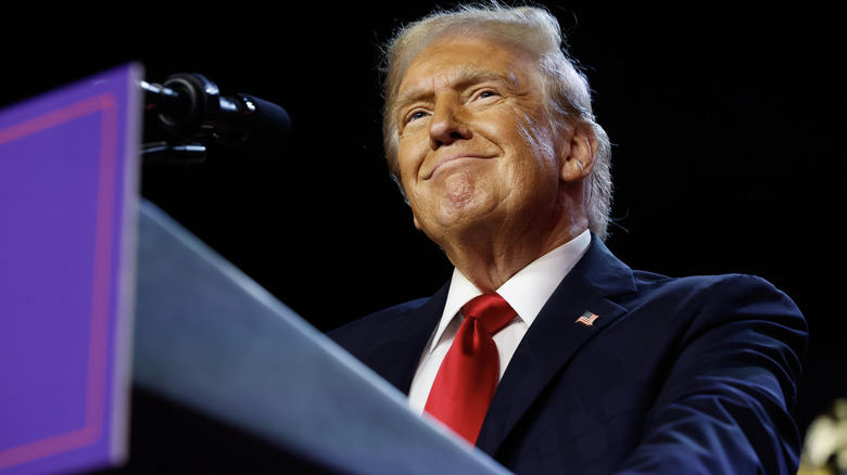 Donald Trump grinning on stage during at a Palm Beach Rally