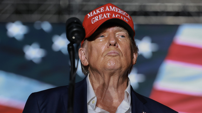 Donald Trump wears a hat behind a podium