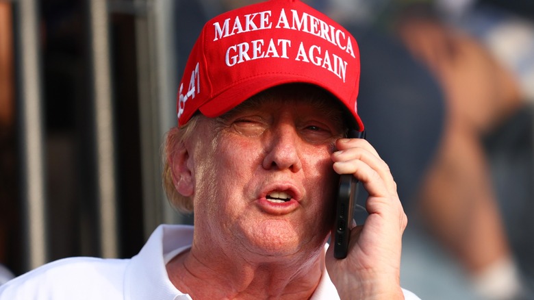 Donald Trump talking on the phone while wearing a MAGA hat