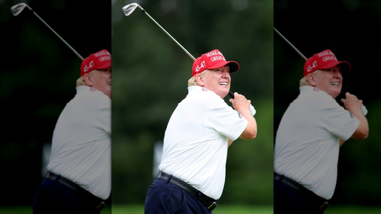 Donald Trump swinging golf club in a MAGA hat