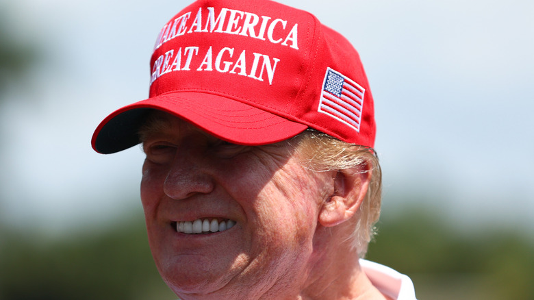 Donald Trump smiling in a red MAGA hat