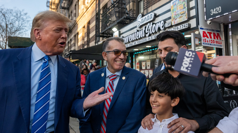 Donald Trump stands outside of bodega with new owner and his son