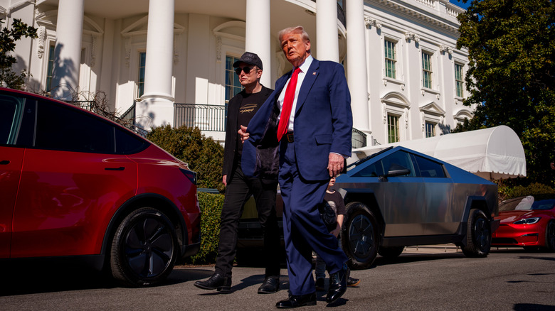 Elon Musk and Donald Trump walking next to red Tesla