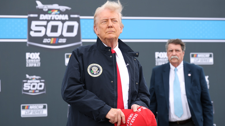 Donald Trump holding MAGA cap Daytona 500