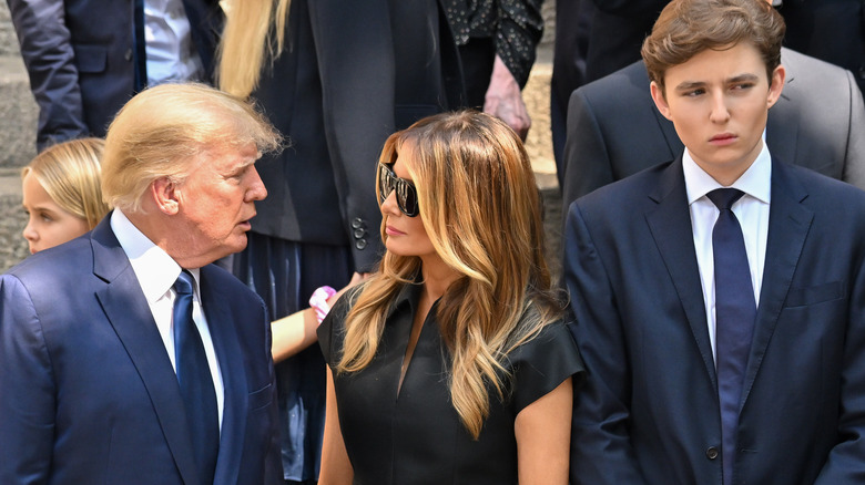 Donald Trump speaking to Melania Trump, Barron Trump standing beside them 