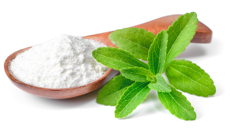 Stevia in a wooden spoon and a leaf of Stevia plant