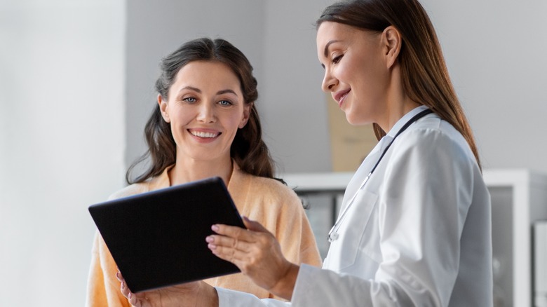 doctor showing woman tablet