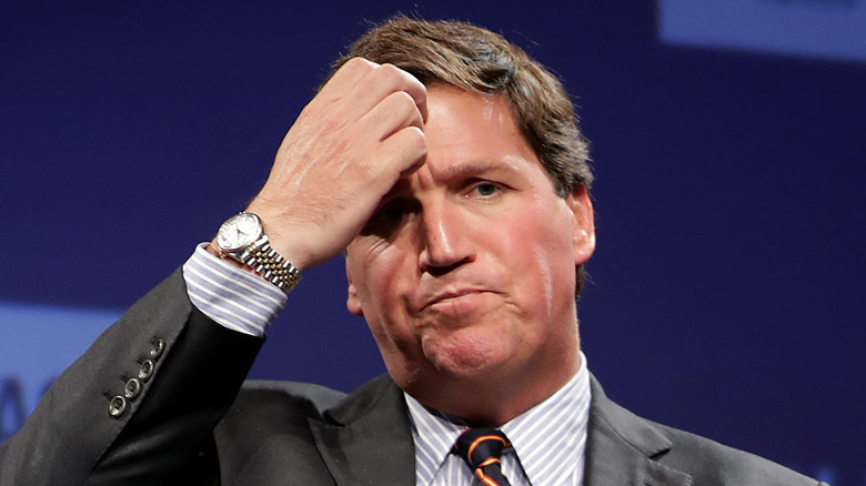 Tucker Carlson scratching his head, looking confused 