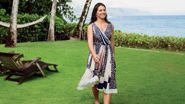 Tulsi Gabbard walking on a grassy beach in a patterned dress