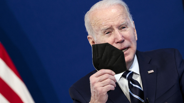 President Joe Biden holds a face mask