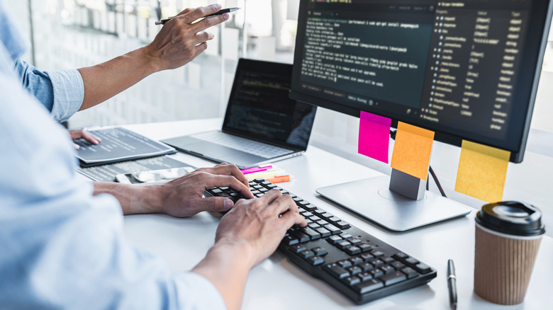 People writing code and working on a desktop computer