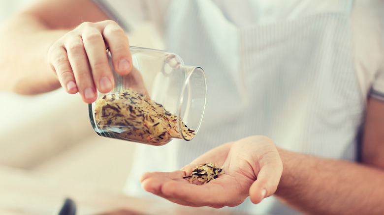 Man emptying a jar of wild rice in his hand