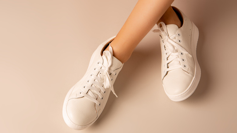 Person wearing white sneakers crosses legs