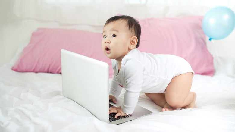 Baby pressing keys on a laptop