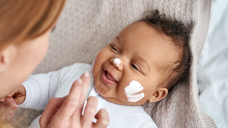 Baby smiling with lotion on face