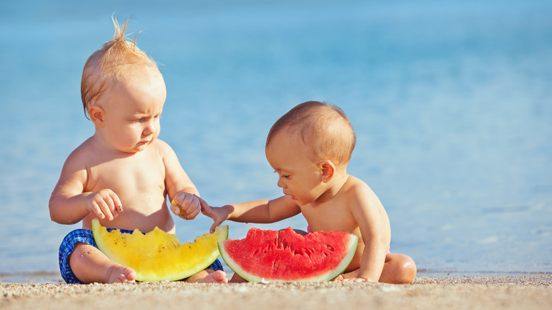 Two babies eating watermelon