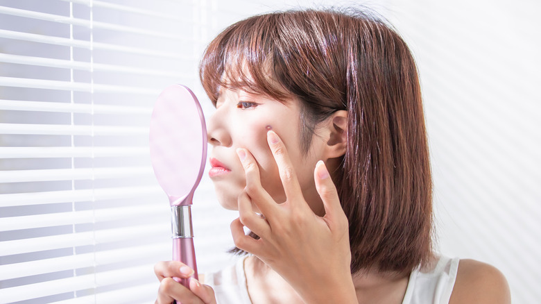 woman looking at acne pustule