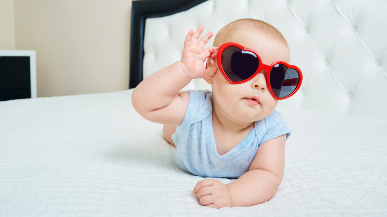 Baby on bed with sunglasses