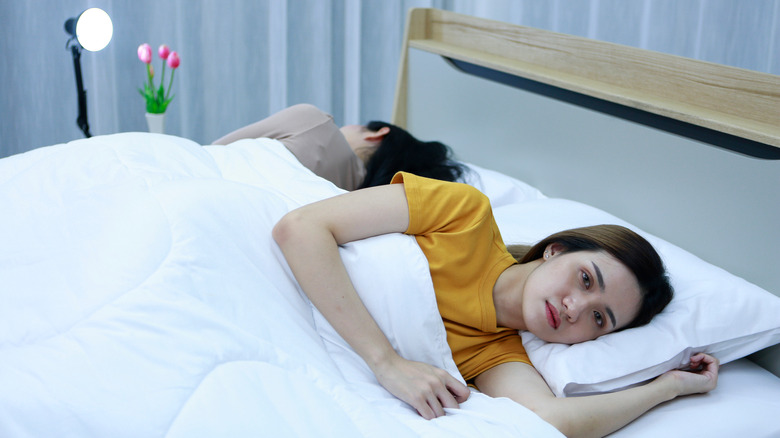 Unhappy couple lying awake in bed