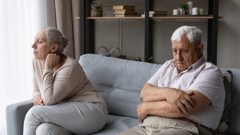 Old unhappy couple sitting on the sofa