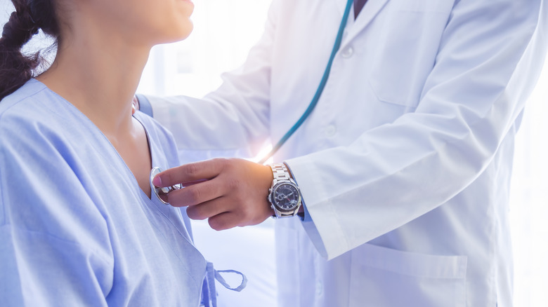 Doctor using stethoscope on patient