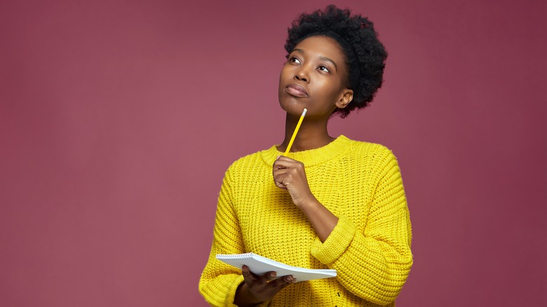 A woman holding a pencil and paper. 