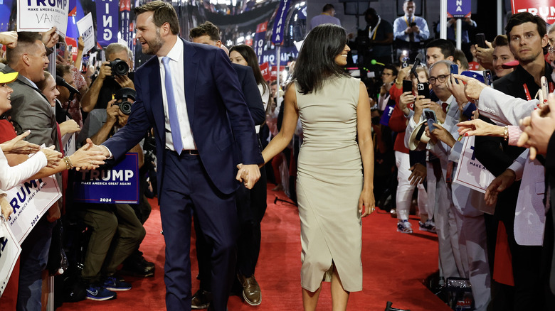 Usha and J.D. Vance holding hands and greeting crowds