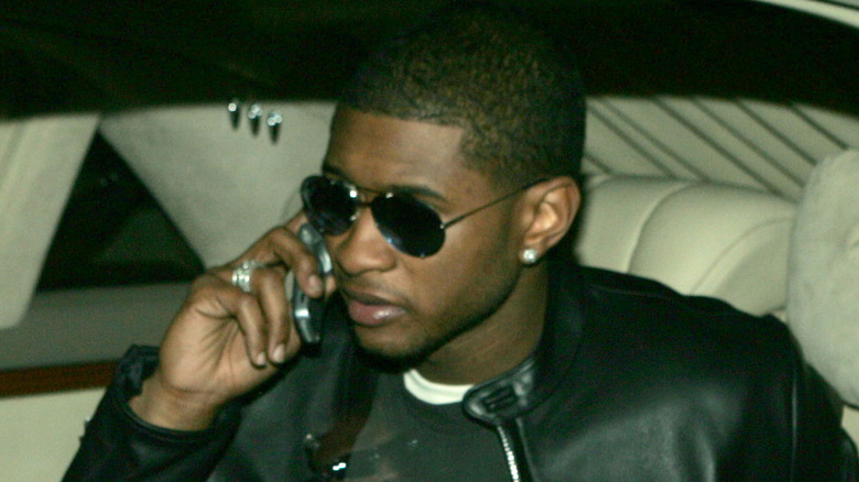 Usher taking a call inside a car
