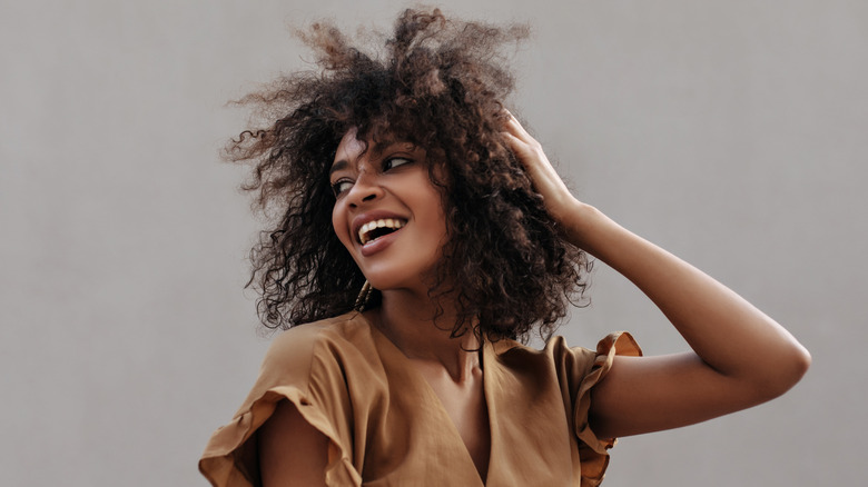 A woman smiling with her hand in her hair. 