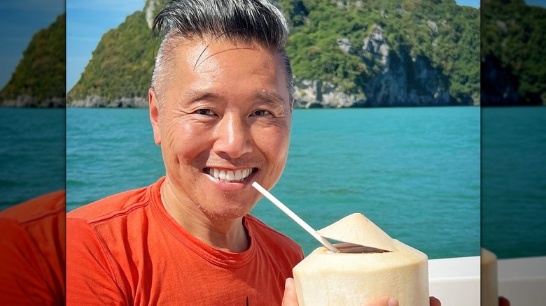 Vern Yip in ocean with tropical drink