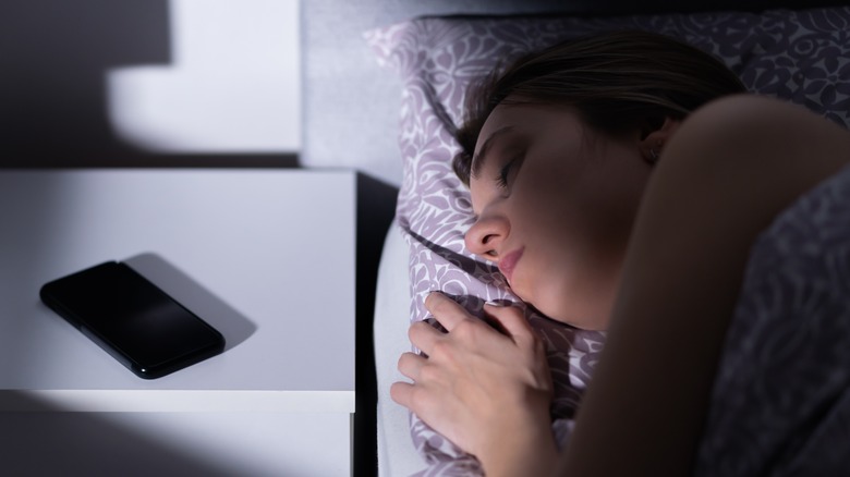 woman choosing sleep over phone